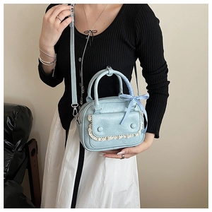 Detail of light blue mini Boston bag with lace trim and blue checkered ribbon bow decoration