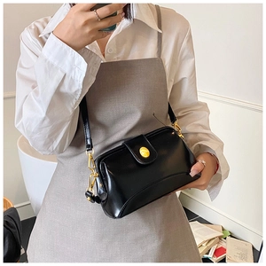 Gros plan du sac bandoulière noir avec boucle dorée et texture en cuir lisse