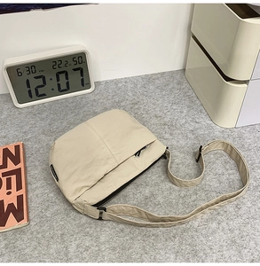 Détail d'un sac bandoulière en nylon beige en forme de demi-lune avec sangle réglable