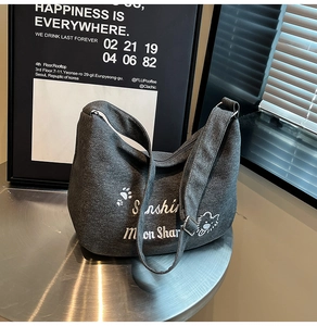 Détail du sac hobo en toile gris foncé avec broderies d'animaux blanches et boucle en métal