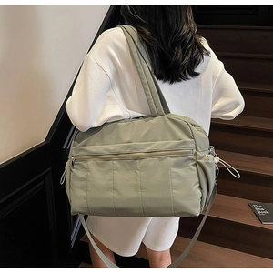 Detail of sage green nylon travel bag with adjustable strap and side pocket on stairs
