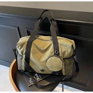 Olivgrüne Reisetasche mit passendem Münztäschchen und Netztaschen auf einem Stuhl