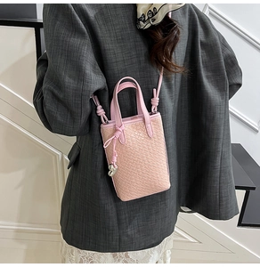 Dettaglio della mini borsa rosa a trama intrecciata con ciondolo a cuore e tracolla