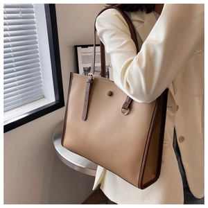 Detail of khaki tote bag with dark brown contrast handles and subtle metal buckle