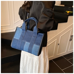Detail of a large contrast denim tote bag featuring a geometric patchwork pattern and strap