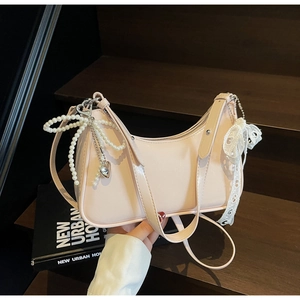 Borsa hobo rosa con ciondolo a fiocco di perle e nastro di pizzo su legno scuro