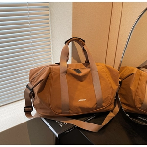 Détail du sac de voyage marron imperméable avec logo NOCO et bandoulière réglable