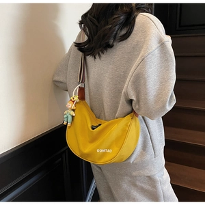 Detailed side view of yellow hobo bag with rainbow strap and star mascot charm