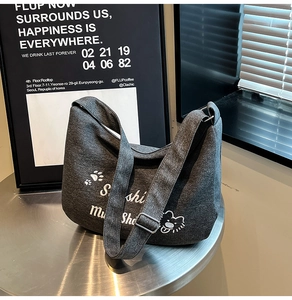 Gros plan d'un sac cabas en toile gris foncé avec broderie ours et lettrage artistique