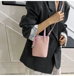 Dettaglio della mini borsa a tracolla intrecciata rosa con ciondolo d'argento su modella