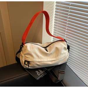 Detail of nylon crossbody bag featuring orange handles and side pleated pocket design