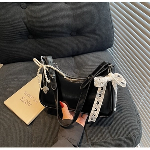 Dettaglio borsa hobo nera con catena di perle, cuore metallico e fiocco in pizzo bianco