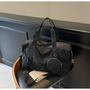 Detail der schwarzen wasserdichten Reisetasche mit Gurt und kleiner Tasche auf einem Stuhl