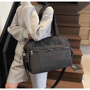Detail of a black quilted travel bag with large capacity and detachable shoulder strap
