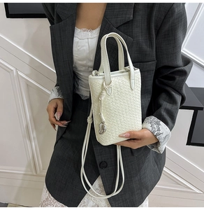 Dettaglio ravvicinato di una borsa tote intrecciata bianca con ciondolo a cuore in argento