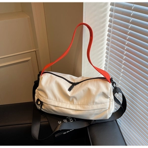 Detail of crossbody pillow bag with orange handle and wide adjustable canvas strap