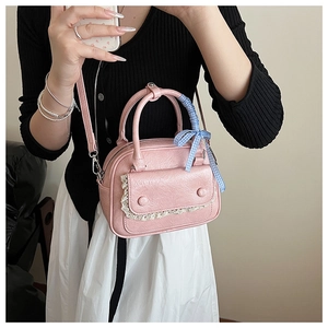 Pink PU leather handbag with lace trim and blue checkered ribbon on a female model