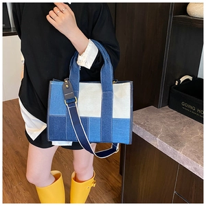 Detail of color-block denim tote bag with striped strap and golden hardware accents