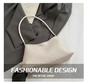 Vue détaillée de la texture tissée du sac à bandoulière crème sur une veste grise
