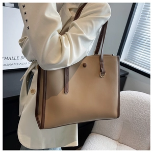Detailed view of camel faux leather tote bag with dark brown trim and double straps
