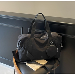 Detail der schwarzen Nylon-Reisetasche mit verstellbarem Gurt und kleinem Münzbeutel
