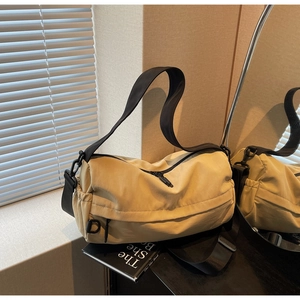 Detail view of khaki nylon crossbody bag with black adjustable strap and drawstring pocket