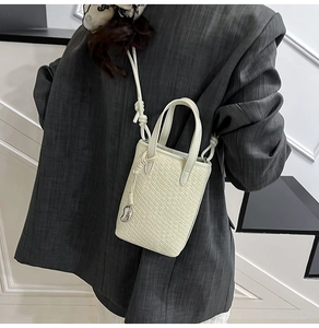 Dettaglio mini borsa crema con trama a coccodrillo e ciondolo a cuore argento sulla modella