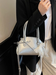 Borsa a tracolla argento a conchiglia con fiocco e perle su sfondo di abito nero elegante
