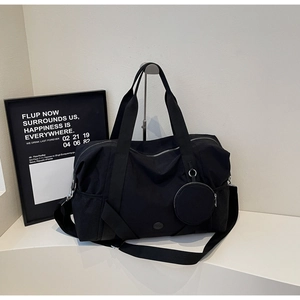 Detail der schwarzen Reisetasche mit abnehmbarem Gurt und kleinem rundem Beutel