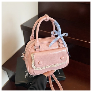 Detailed shot of pink glossy mini bag featuring white lace trim and checkered bow ribbon
