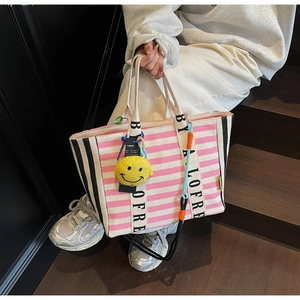 Striped canvas tote bag with letter print straps and a yellow smiley face charm detail