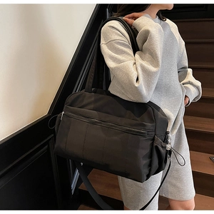 Detail of black large capacity travel duffel bag with side pockets on a model