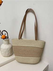 Summer straw tote bag with brown leather handles and striped woven design for vacation