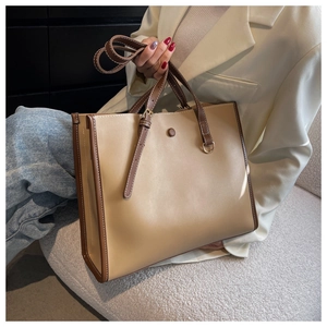 Macro shot of two-tone tote bag with white stitching details and detachable shoulder strap