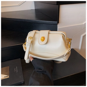 Détail d'un sac bandoulière blanc crème avec boucle ambrée et finitions dorées chic