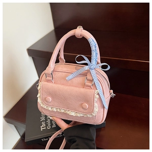 Detail of pink mini handbag featuring lace pocket, plaid bow, and faux leather texture