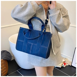 Detail view of denim tote with contrast stitching and H-shaped patchwork structure