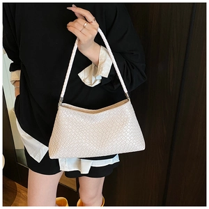Détail de la texture en cuir tressé blanc d'un sac à bandoulière porté par un modèle