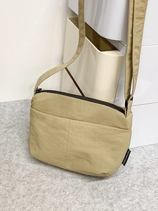 Sac bandoulière en nylon kaki avec large sangle et étiquette de marque minimaliste