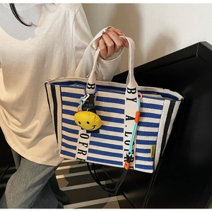 Close-up of blue striped canvas tote bag with contrast black side panels and lettered handles