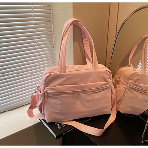 Pink quilted duffel bag featuring multiple zippers, side pockets and wide shoulder strap