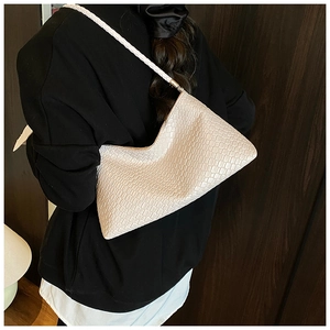 Détail d'un sac à bandoulière blanc à motif crocodile avec bandoulière tissée élégante