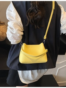 Borsa a secchiello gialla alla moda con motivo litchi e tracolla, indossata da modella