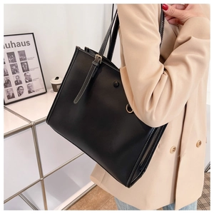 Detail of black leather tote bag featuring white contrast stitching and adjustable strap