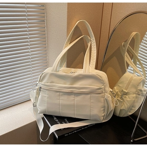 Detail of cream large travel tote bag with quilted front pocket and side storage pockets