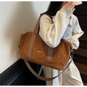 Détail du sac de sport marron avec logo NOCO et compartiment inférieur zippé séparé