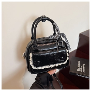 Detail of black patent leather mini bag with lace pocket and gingham ribbon handle
