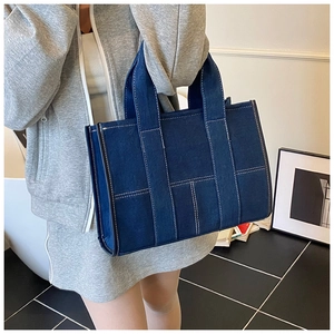 Detail of dark blue denim tote bag with contrast stitching and wide shoulder straps
