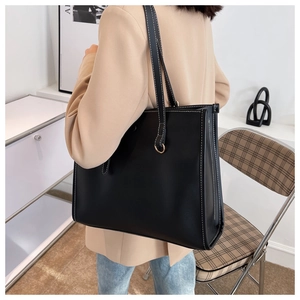 Detail of black tote bag with white contrast stitching and long leather shoulder straps