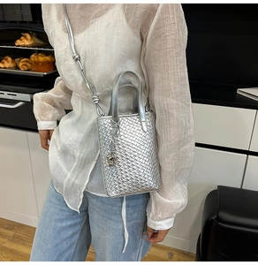 Dettaglio della borsa tote intrecciata argento con trama metallica e ciondolo a cuore
